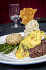 filet mignon steak covered in crab meat wth garlic mashed potatoes, mushroom cap, and asparagus at a gourmet restaurant