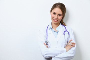 Fototapeta premium Friendly smiling young female doctor, standing near wall