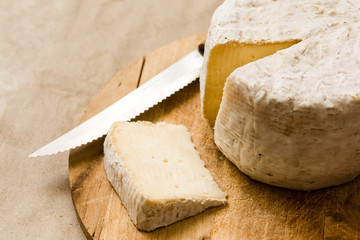 slice of mature cheese and whole caciotta on the chopping board