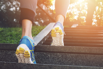 Athlete runner feet running in nature, closeup on shoe. Female athlete running on stairs. Woman...