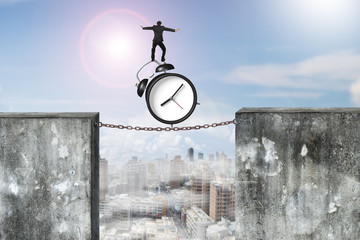 Businessman balancing alarm clock on rusty chain connected concr