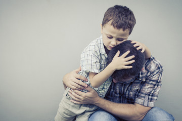 sad son hugging his dad near wall