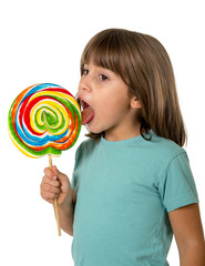 4 or 5 years old child girl eating and licking with tongue big multicolor spiral lollipop candy