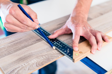 Arbeiter mit Winkel reißt Markierung auf Parkett