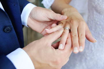 Obraz na płótnie Canvas Groom wears a wedding ring a bride