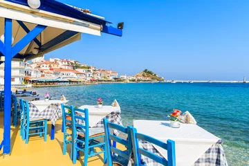 Photo sur Plexiglas Santorin Tables with chairs in traditional Greek tavern in Kokkari town on coast of Samos island, Greece