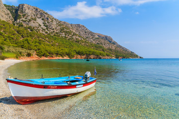 Naklejka na ściany i meble Traditional Greek fishing boat in sea bay on secluded beach, Samos island, Greece