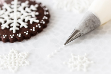 Decorating cookies with royal icing snow flakes.