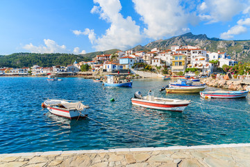 Fototapeta na wymiar Fishing boats in Kokkari bay with colourful houses in background, Samos island, Greece