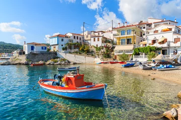 Rolgordijnen Vissersboot in Kokkari-baai met kleurrijke huizen op achtergrond, Samos-eiland, Griekenland © pkazmierczak