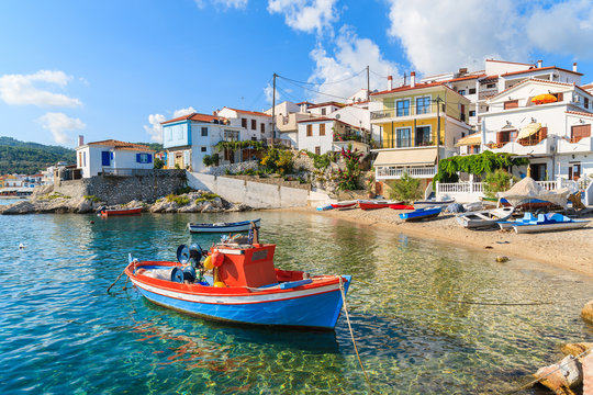 Fototapeta Fishing boat in Kokkari bay with colourful houses in background, Samos island, Greece