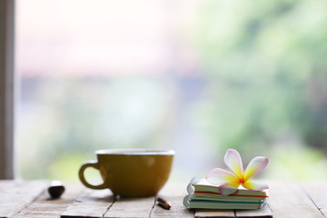 Notebook and cup with flower on wooden table