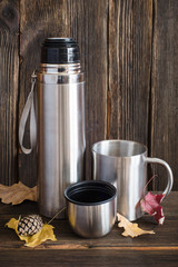 Silver opened thermos flask and metal travel cup