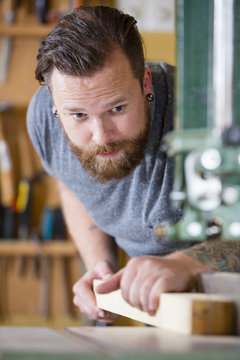 Craftsman using bandsaw for splitting wood plank in workshop