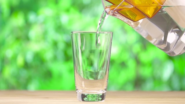 Clean water from water filter pouring in to the glass