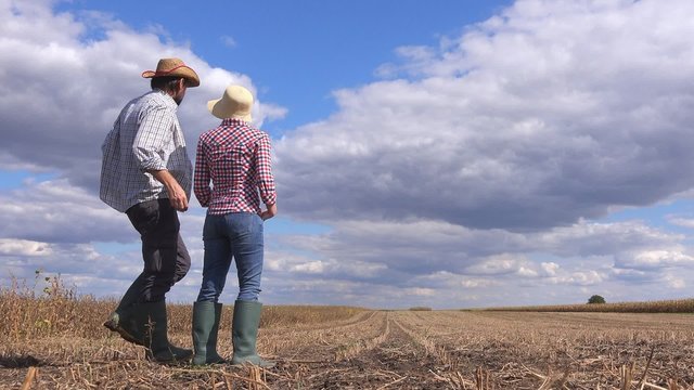 Young farmer couple planning new seeding season on arable land, organic farming production at cultivated field.