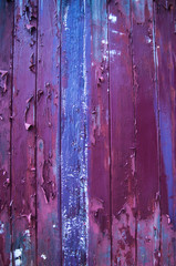 Flaking paint of purple and blue on wood