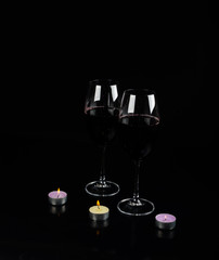 glass of wine and a candle on a black background