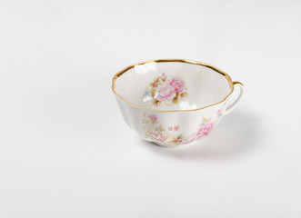 Fototapeta na wymiar Antique porcelain tea cup with floral painting on white backgrou