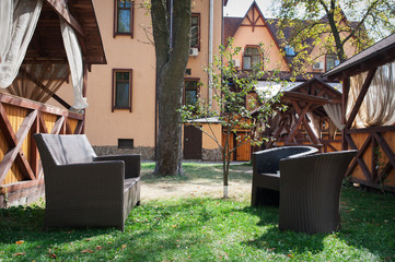 brown leather sofa and two chairs in the garden near the house