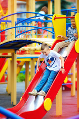 group of happy kids sliding on colorful playground