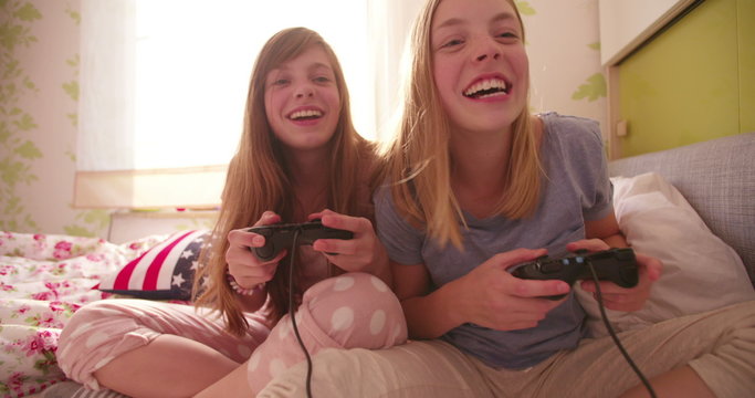 Girl jokingly pushing her friend while playing computer games