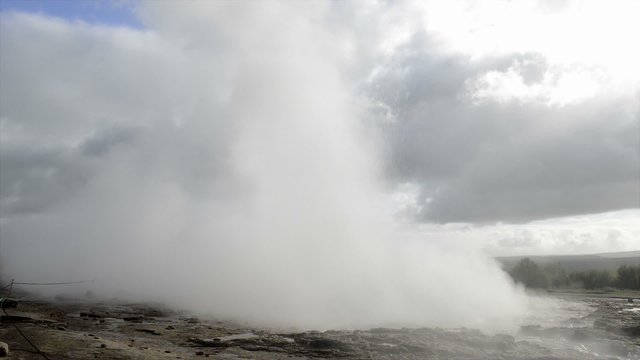 Eruption of the Strokkur Geyser in Iceland on a cloudy day.