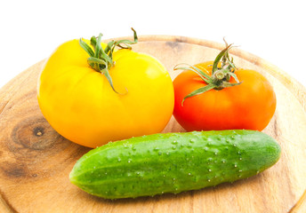 tomatoes and cucumber on wooden cutting board