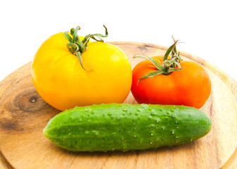 two tomatoes and cucumber on wooden cutting board