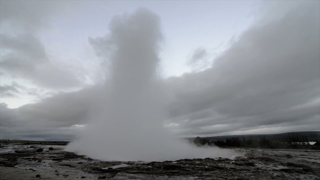 Eruption of the Strokkur Geyser in Iceland on a cloudy day.