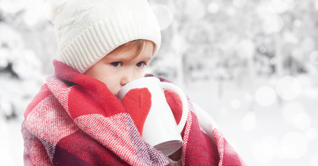 happy child girl with cup of hot drink on cold winter outdoors