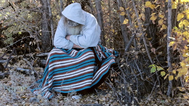 Homeless man sitting in trees with blanket HD 0149