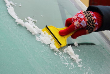 Hand of woman scraping ice from car windscreen