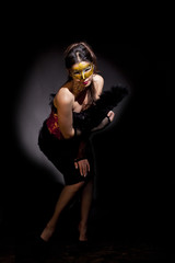 Beautiful and mysterious masked young woman on black background