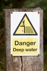 Danger Deep Water sign on wooden post besides river