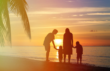 Fototapeta na wymiar happy family with two kids walking on sunset beach