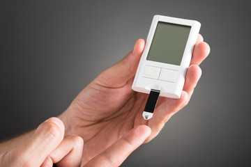 Person Checking Blood Sugar Level With Glucometer