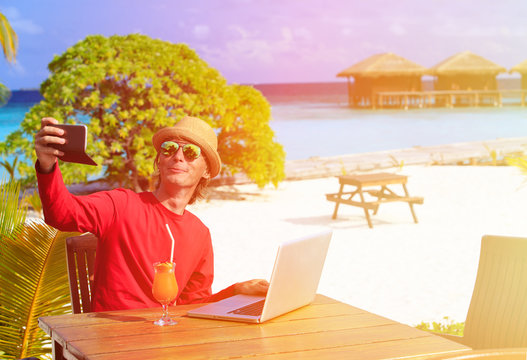 Young man with laptop at luxury resort making selfie