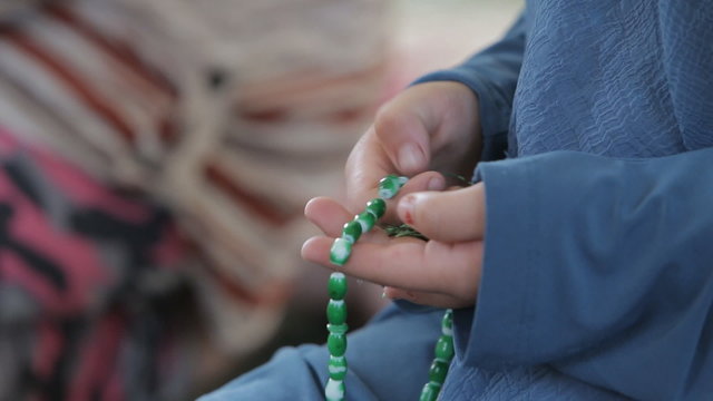 Young muslim girl with rosary praying in mosque