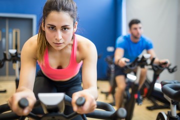 Focused couple using exercise bikes