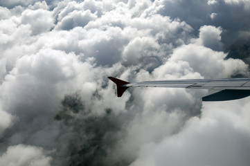 The wing of the Airbus above the clouds in the sky, view from above the clouds, flying over clouds in a plane, the boundless space, the atmosphere and meteorology, from the window of the porthole.