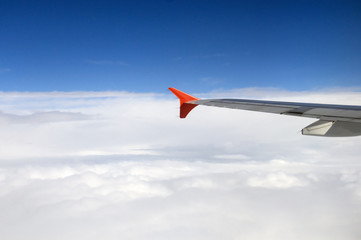 Fototapeta premium The wing of the Airbus above the clouds in the sky, view from above the clouds, flying over clouds in a plane, the boundless space, the atmosphere and meteorology, travel on a passenger plane