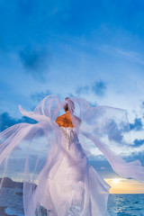 Fototapeta na wymiar YOung bride by the sea at sunset