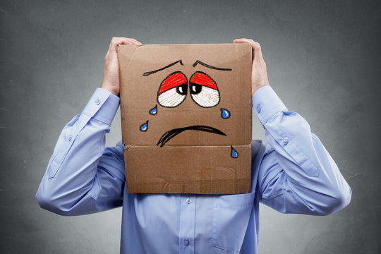 Man With Cardboard Box On His Head Showing Sad Expression