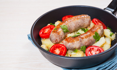 Potatoes with sausages in a frying pan