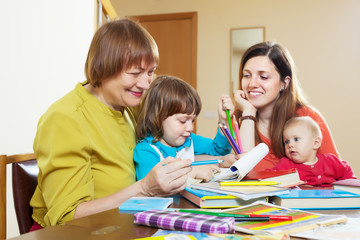 Happy woman  with daughter and grandchildren sketching  on paper