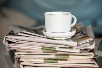 Stack of newspapers with a cup of coffee
