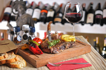 T-Bone steak barbecue with fried potato and red wine on wood table