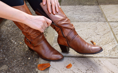 Woman zipping up high-heeled tan leather boots