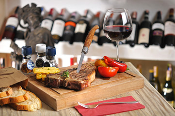 T-Bone steak barbecue with fried potato and red wine on wood table
